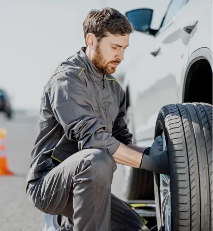 Mec&aacute;nico reparando las llantas de un veh&iacute;culo particular en referencia a la cobertura del seguro de responsabilidad civil vehicular de Seguros Caracas