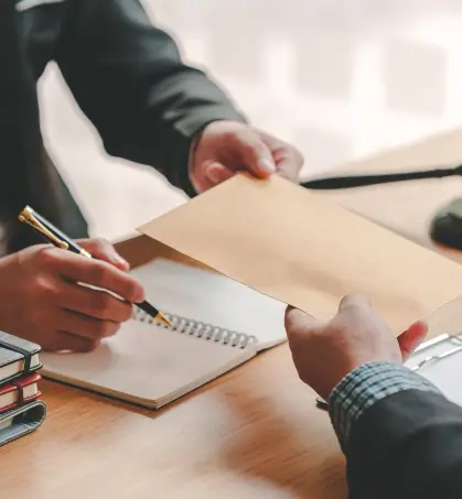 Dos personas intercambiando un sobre en referencia a la p&oacute;liza de fianza de seguros patrimoniales de Seguros Caracas