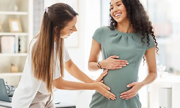 Doctora atendiendo a una paciente embarazada en Maternidad en referencia a las p&oacute;lizas de salud de Seguros Caracas y sus beneficios